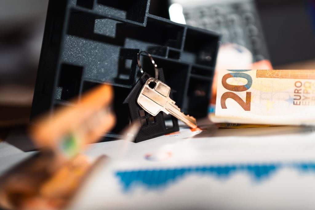 Clés maison, billets euros et graphiques financiers