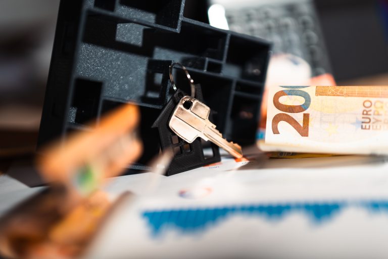 Clés maison, billets euros et graphiques financiers
