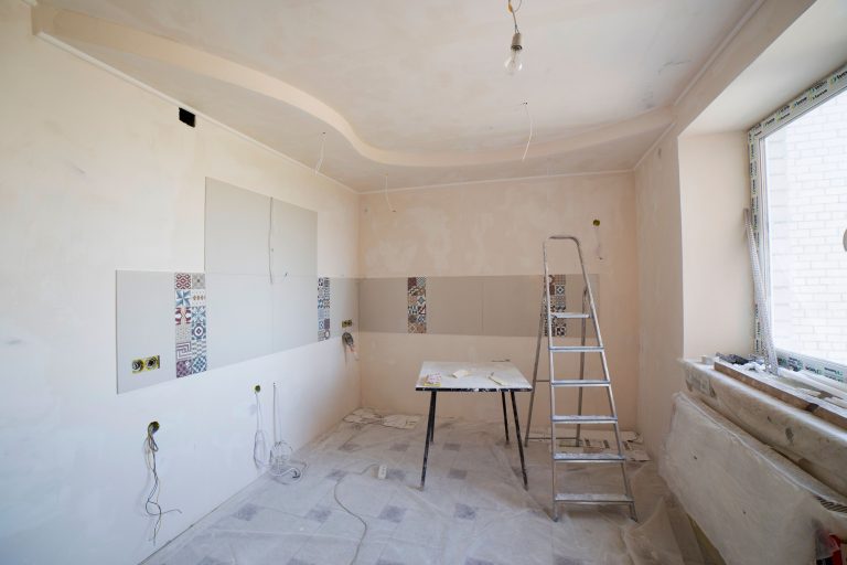 Spacious kitchen under renovation with ladder and tools, showcasing a fresh new design. Cuisine spacieuse en rénovation avec échelle et outils, présentant un design neuf et frais.