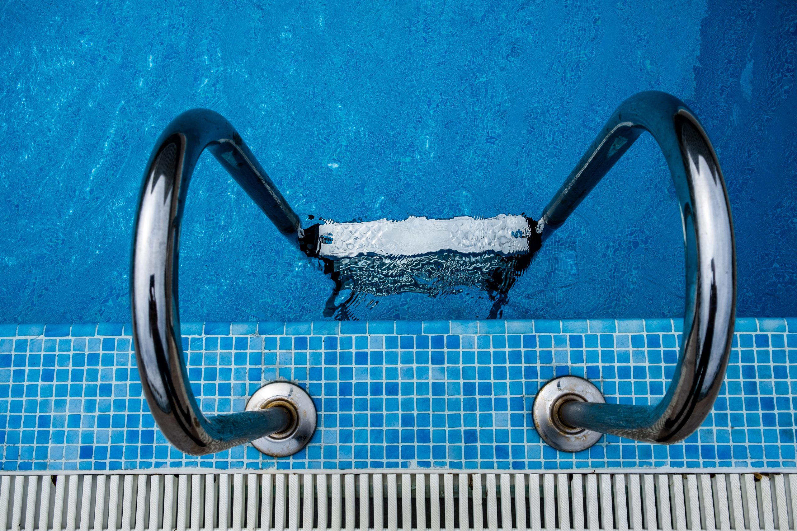 Vue aérienne d'une échelle inox dans piscine bleue