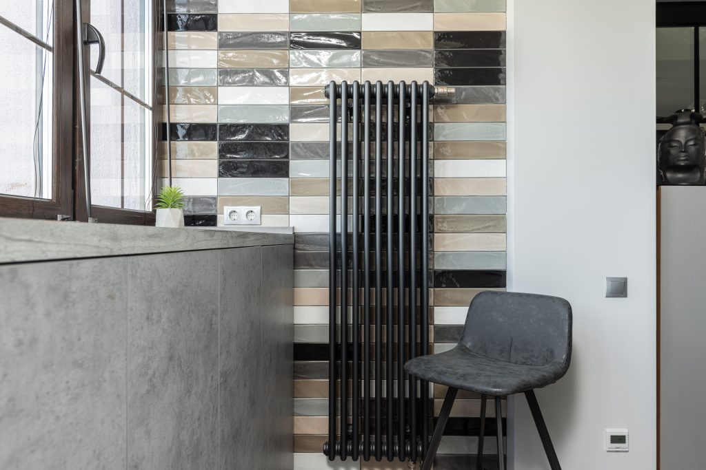 Stylish home interior featuring a tiled wall, radiator, and designer chair. Intérieur de maison élégant avec mur carrelé, radiateur et chaise design.
