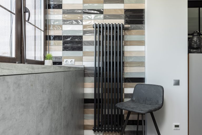 Stylish home interior featuring a tiled wall, radiator, and designer chair. Intérieur de maison élégant avec mur carrelé, radiateur et chaise design.