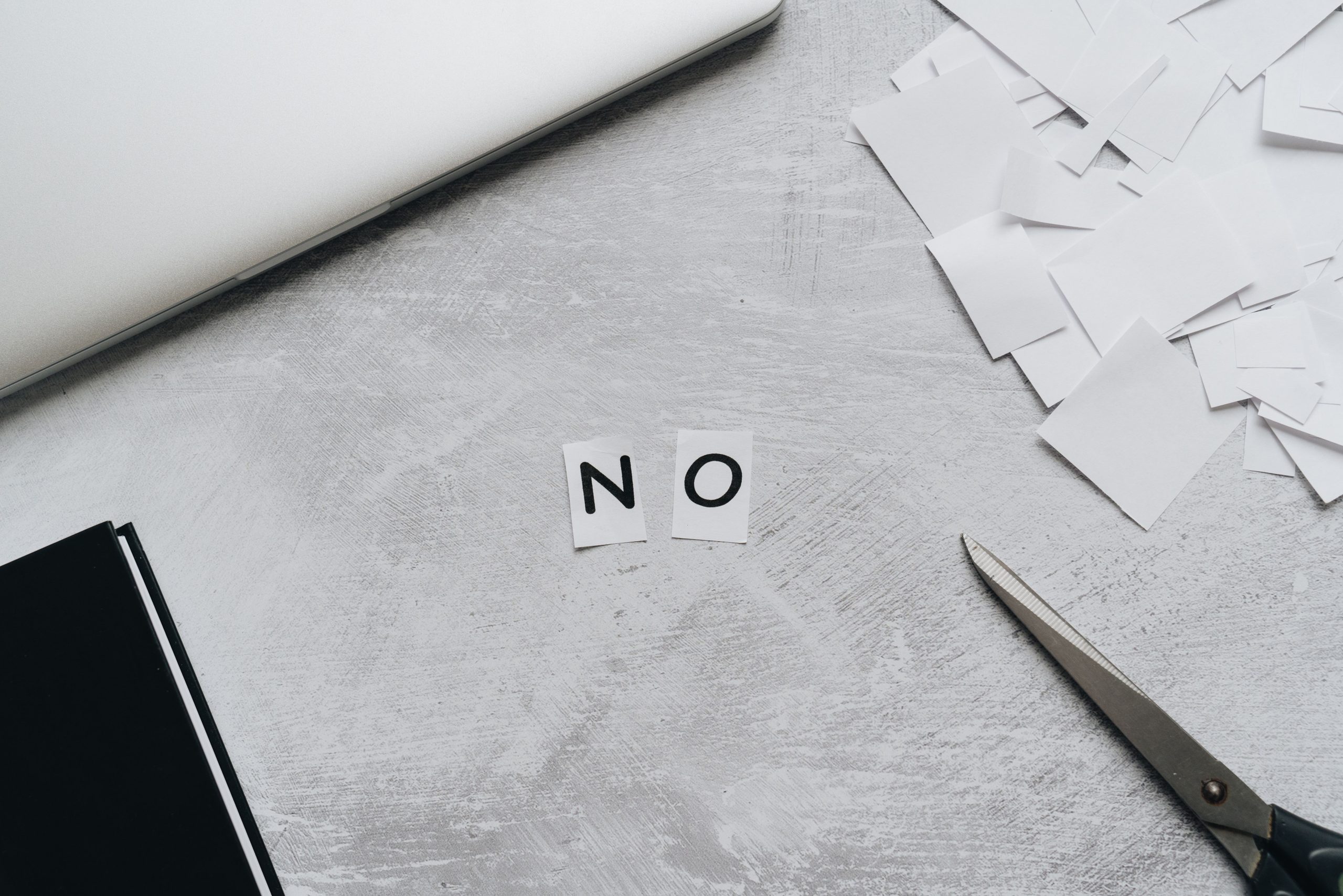Le mot NON formé avec papiers et ciseaux