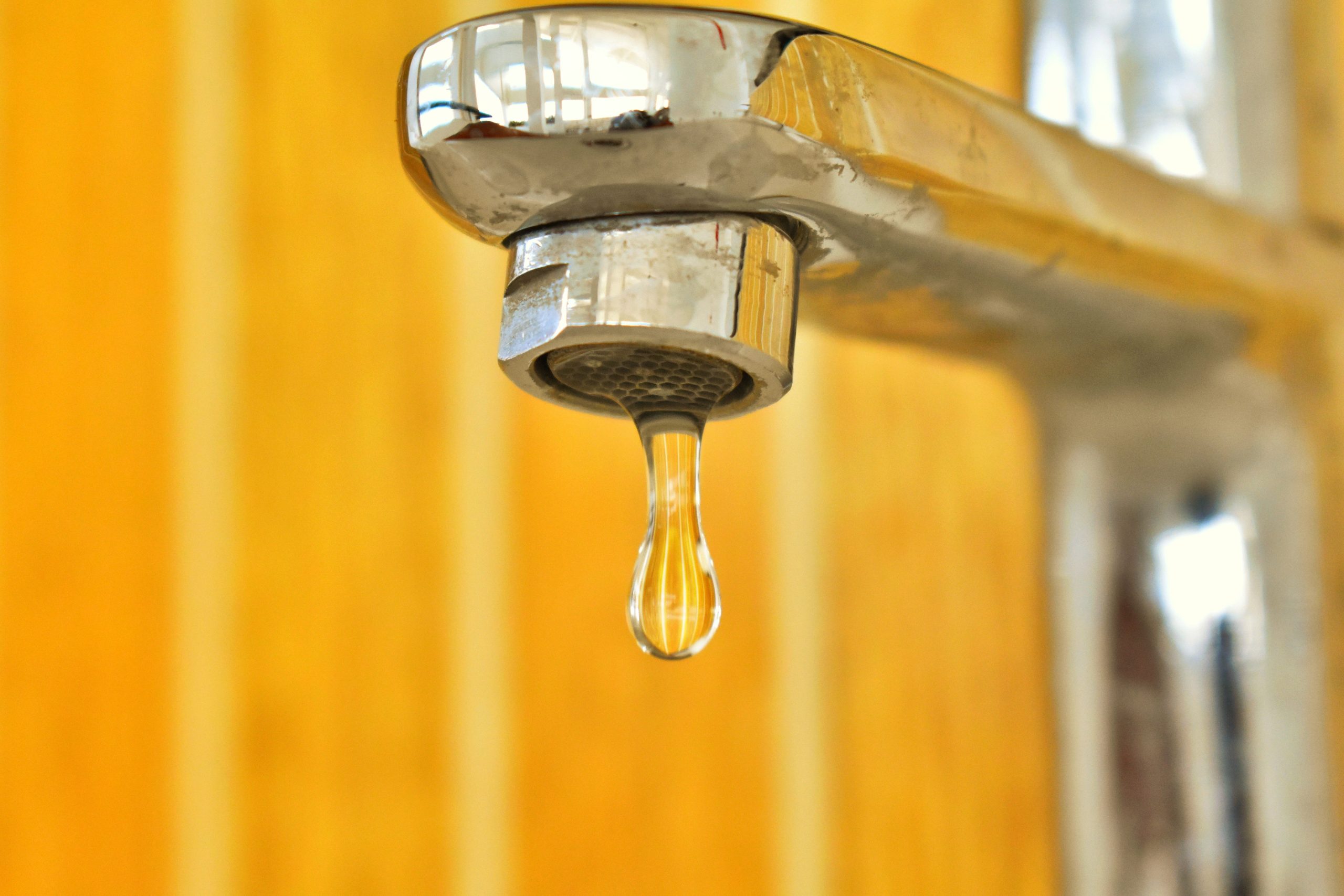 Goutte d'eau suspendue à un robinet acier