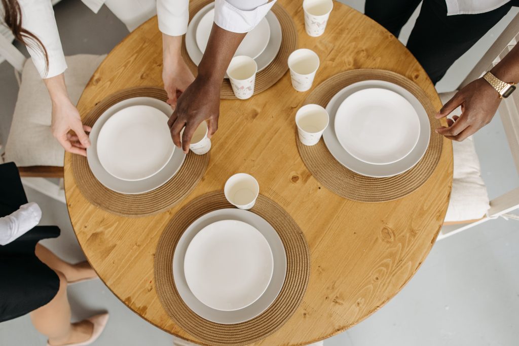 Trois adultes dressent une table ronde en bois