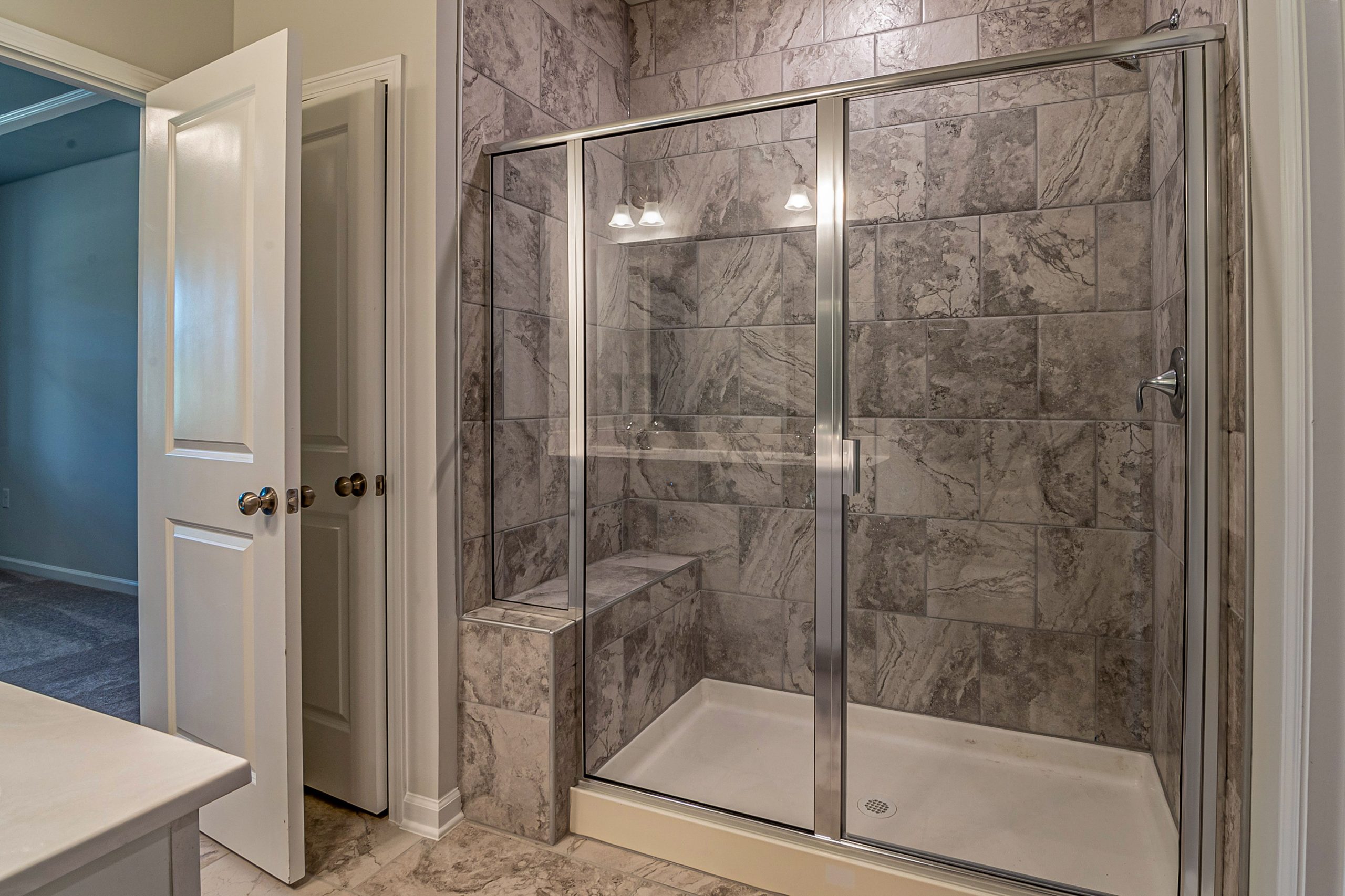 Salle de bain moderne avec douche marbre et portes vitrées