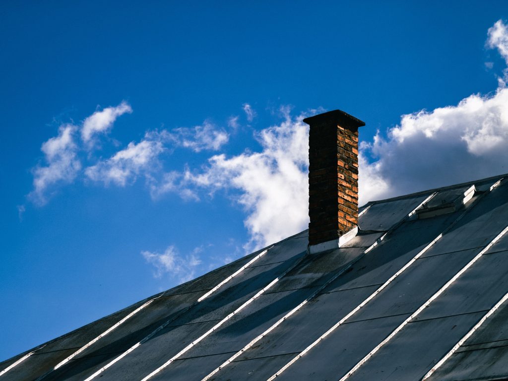 Toit métallique avec cheminée en brique sous ciel bleu