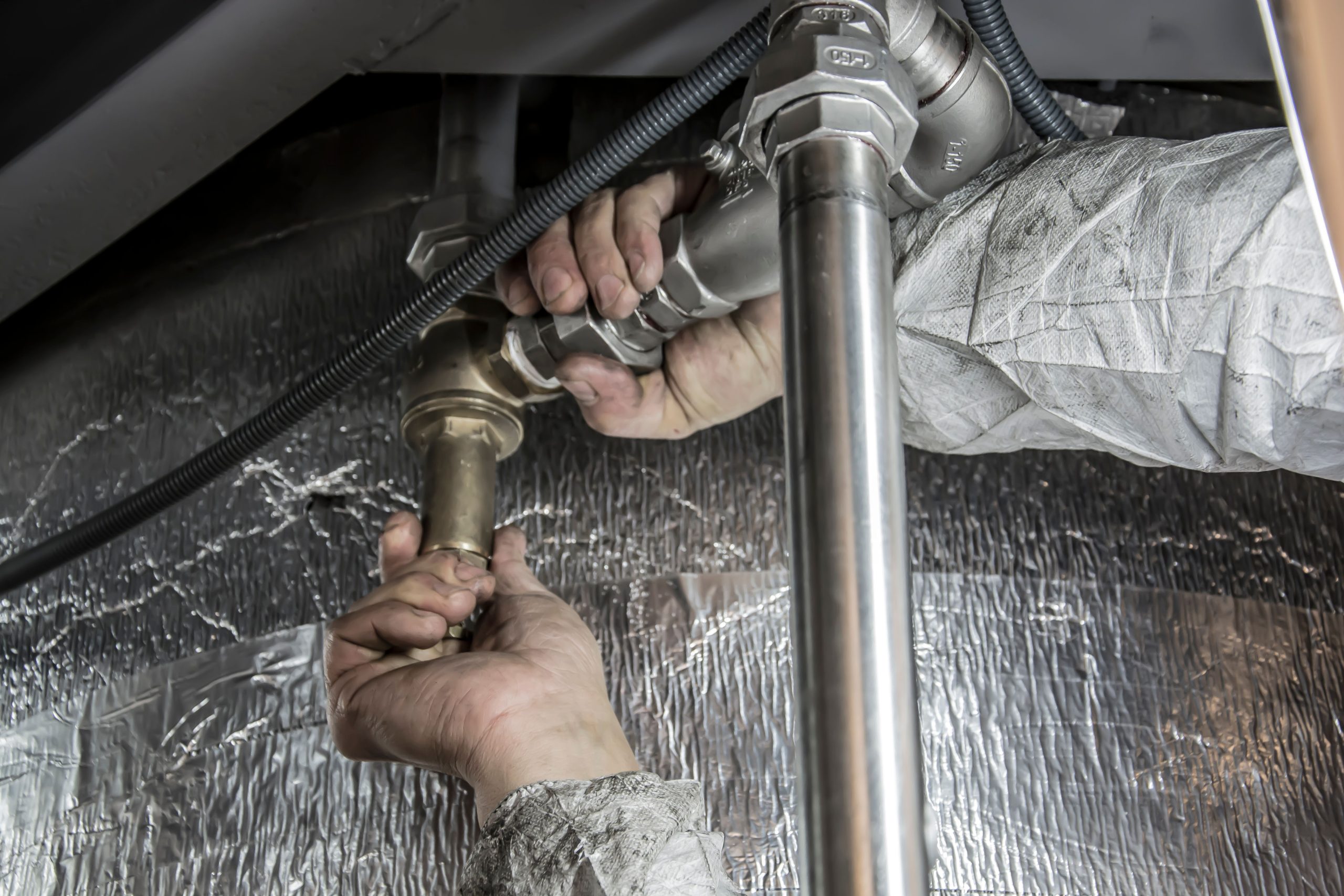 Plombier installant des tuyaux acier avec expertise