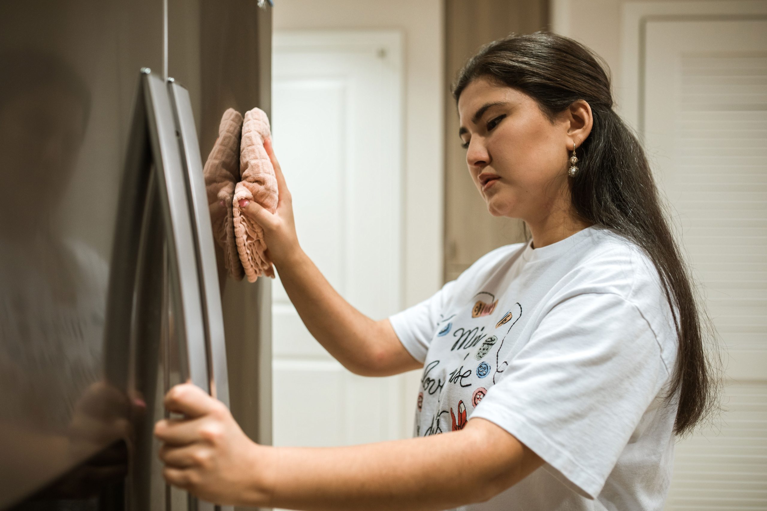 Femme nettoie porte refrigérateur cuisine moderne