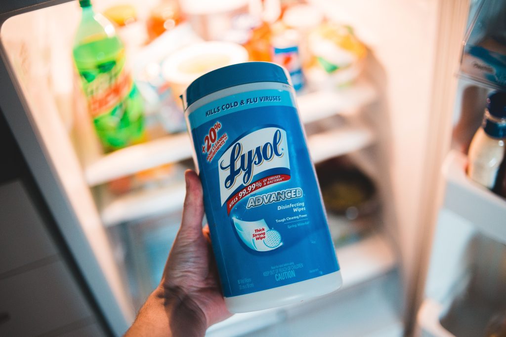 Personne nettoyant frigo avec lingettes antibactériennes