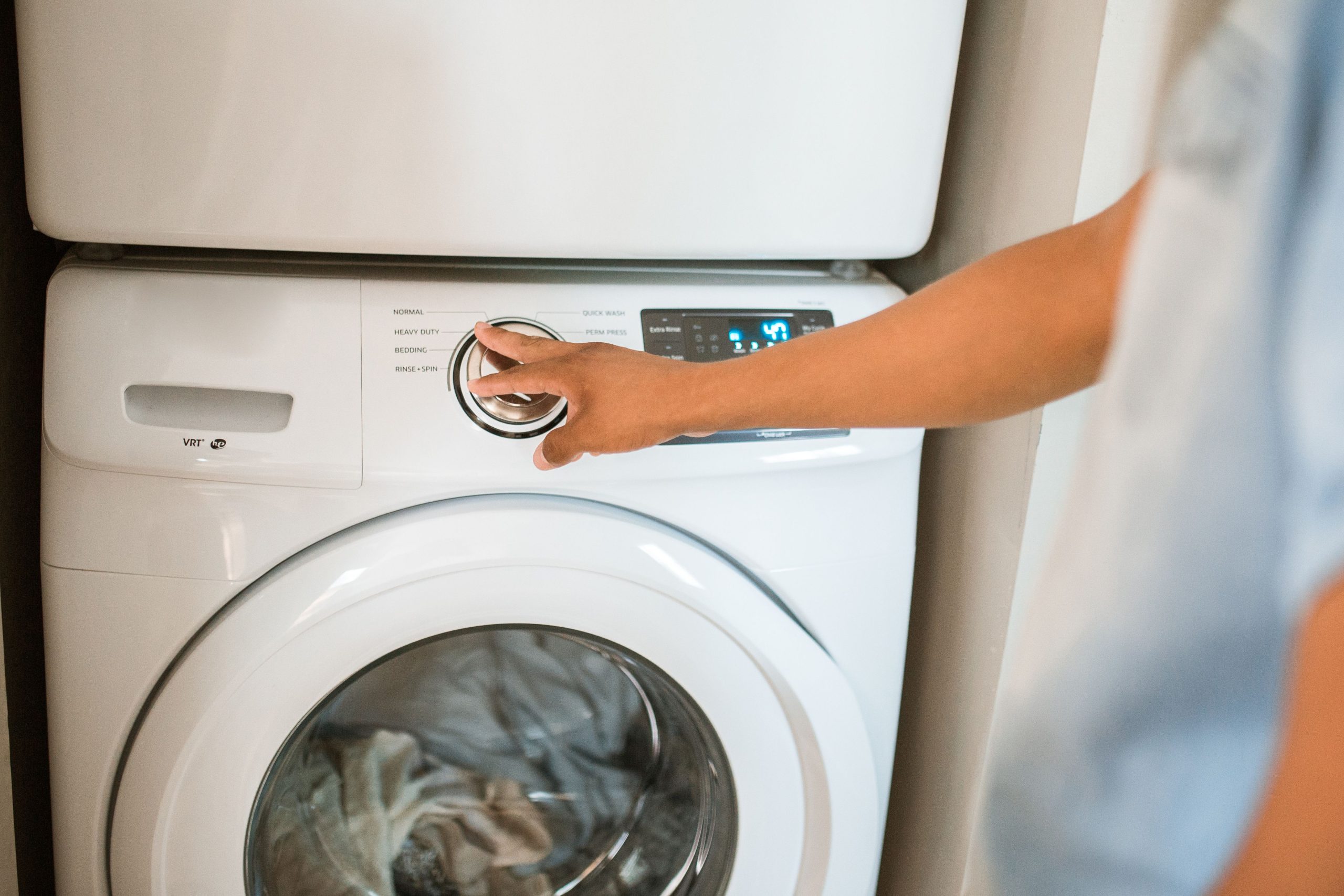 Personne ajustant un lave-linge dans une buanderie